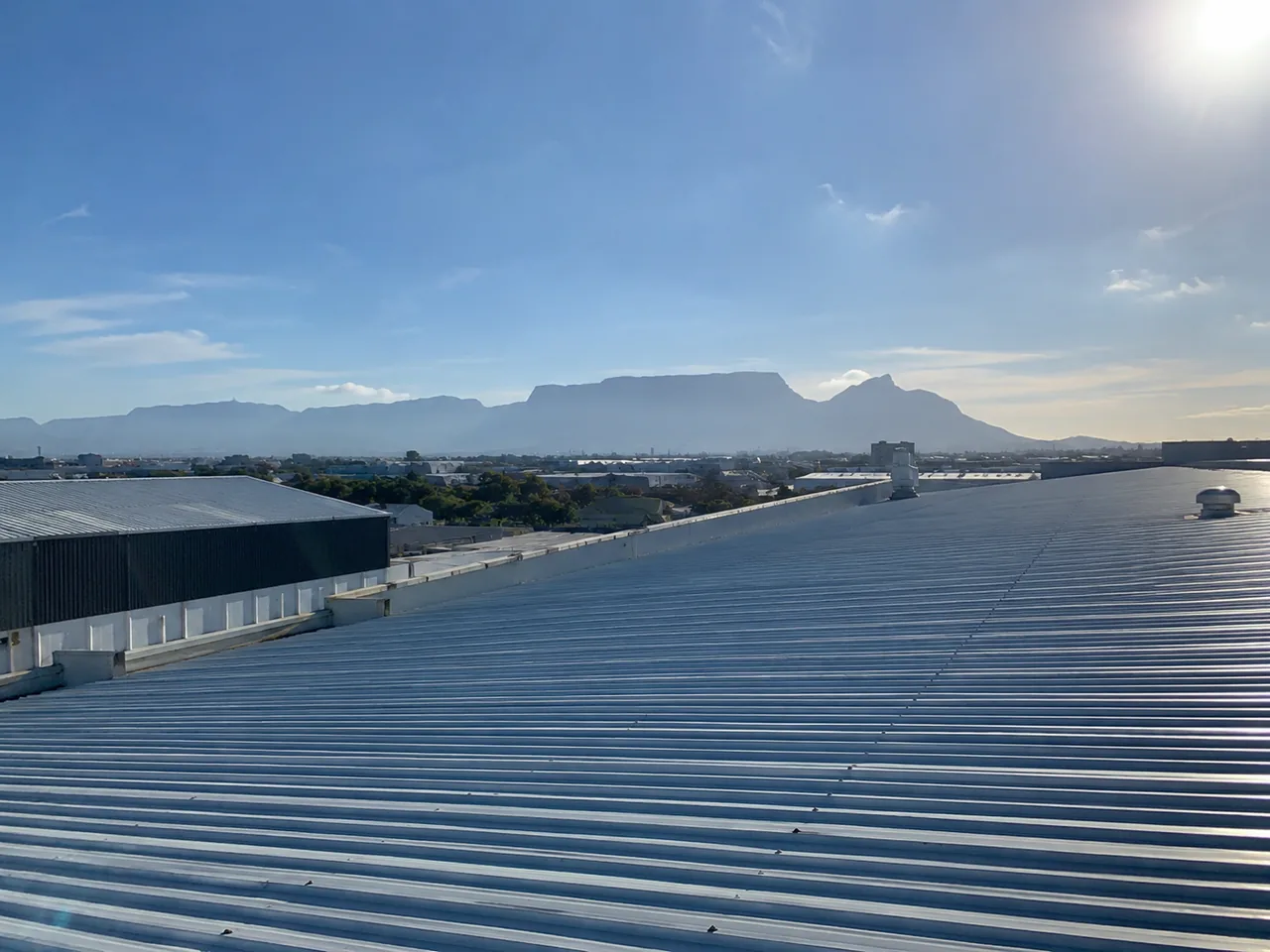 Large corrugated metal roof with roof vents and adjoining industrial buildings