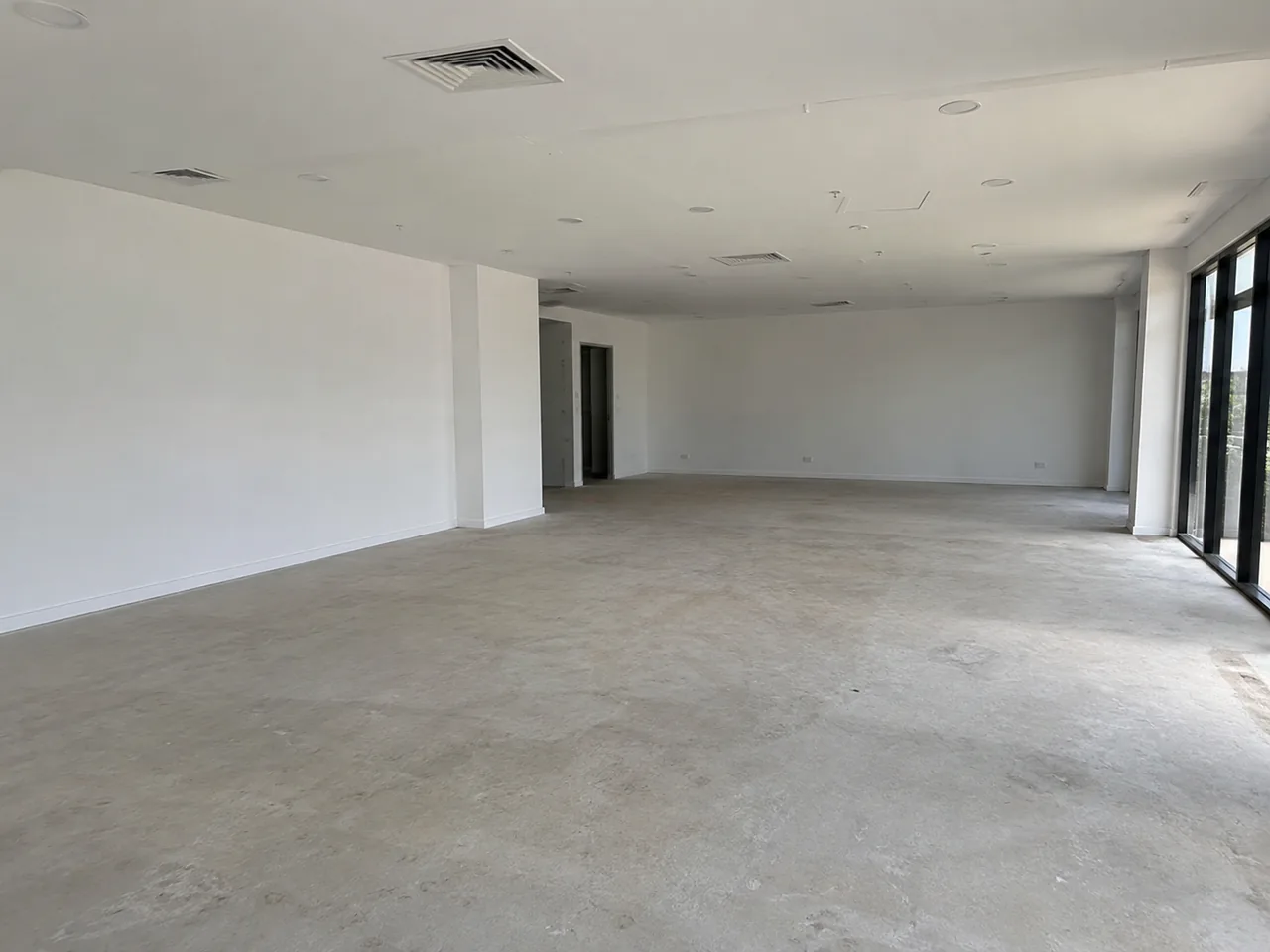 Vacant commercial unit with white walls, ceiling fittings and a bare floor
